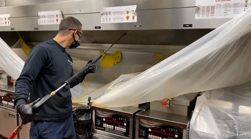 Technicien nettoyant une hotte professionnelle dans un restaurant du Yvelines
